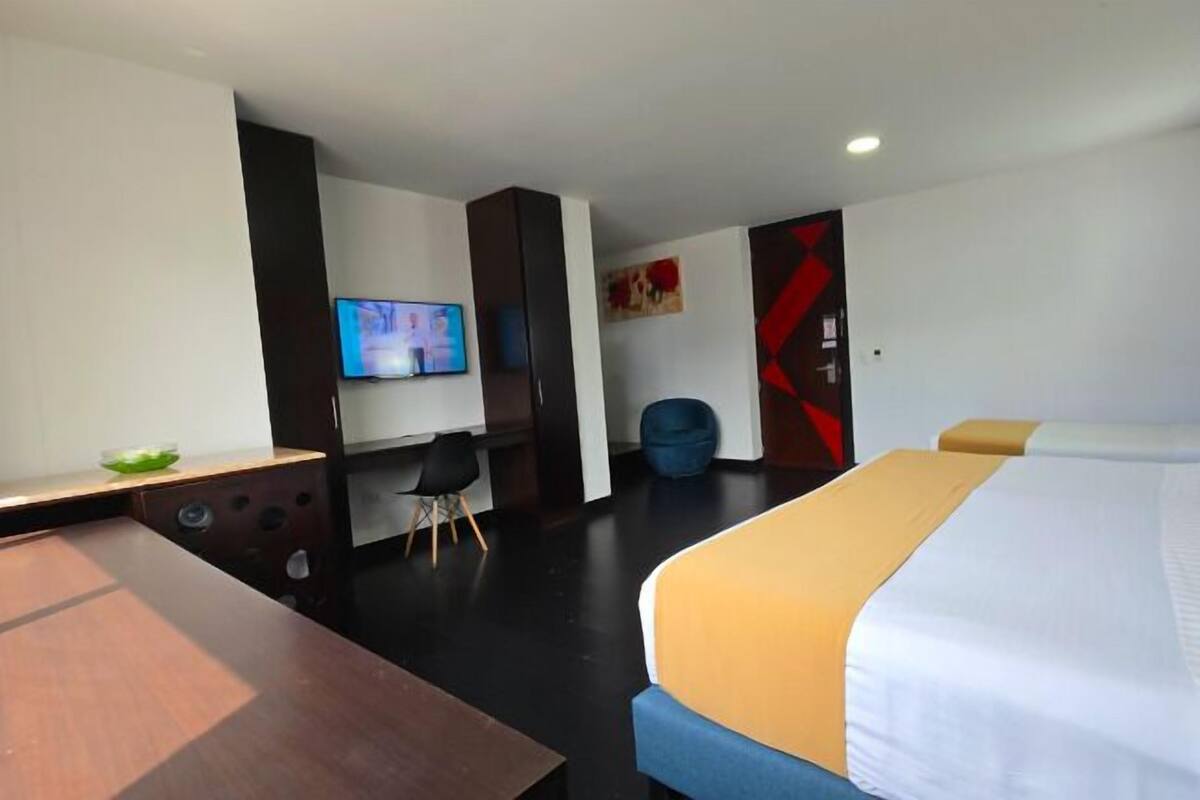 A hotel room with a bed, a desk, a television, and a chair.