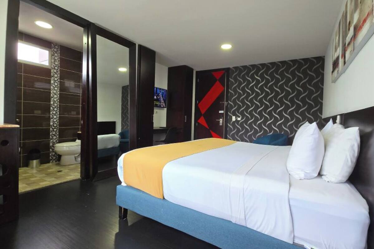 A hotel room with a bed, a desk, a TV, and a bathroom.
