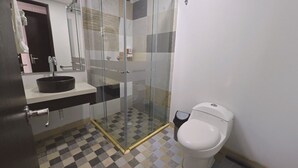 A bathroom with a glass-enclosed shower, a white toilet, and a black sink on a white countertop. - Hotel City Center Corferias (Bogotá)