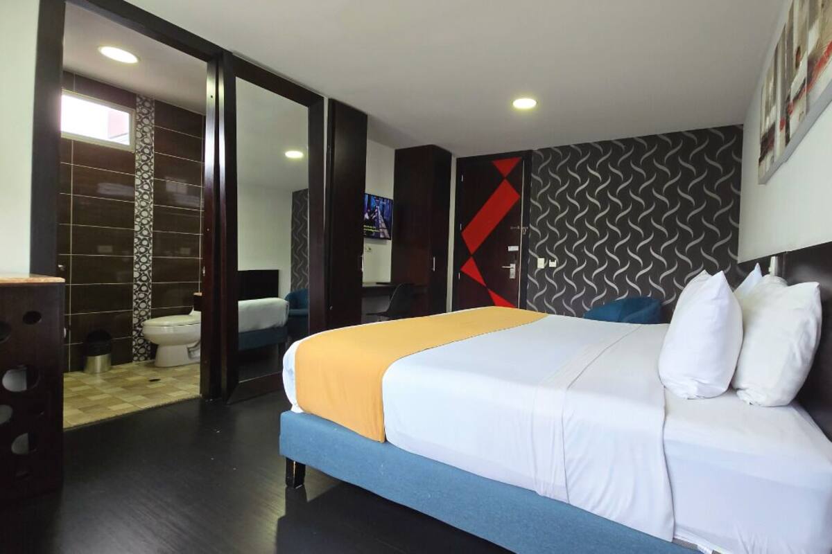 A hotel room with a bed, a desk, a wardrobe, and a bathroom.