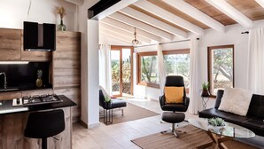 A modern kitchen with a built-in stove, a black chair, a glass coffee table, and a sofa with a cushion. - Country House 'Ses Cases' with Mountain View, Private Pool and Wi-Fi (Manacor)