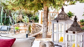 A patio area with a white table, cushions, a lantern, and a stone wall. - Country House 'Ses Cases' with Mountain View, Private Pool and Wi-Fi (Manacor)