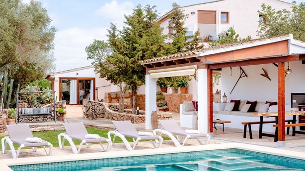 A pool area with lounge chairs, a pergola, and a building with a tiled roof. - Country House 'Ses Cases' with Mountain View, Private Pool and Wi-Fi (Manacor)