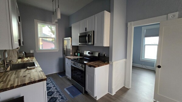 A modern kitchen with stainless steel appliances, a wooden countertop, and a view of the outside. - Cozy 3-beds house in NE Portland. (Portland)