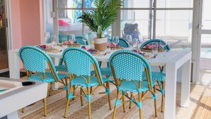 A dining area with a white table, turquoise patterned chairs, and a potted plant. - Costal Escape: Heated Pool~Tiki Bar~Hot Tub~Fire Pit~Acarde~Pool Table (Bradenton)