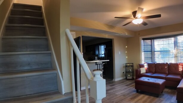 A staircase with wooden steps and white railings leading to a kitchen area. - 4Bd 2Ba 7 Person Sleeper-  King Bed (Somerdale)