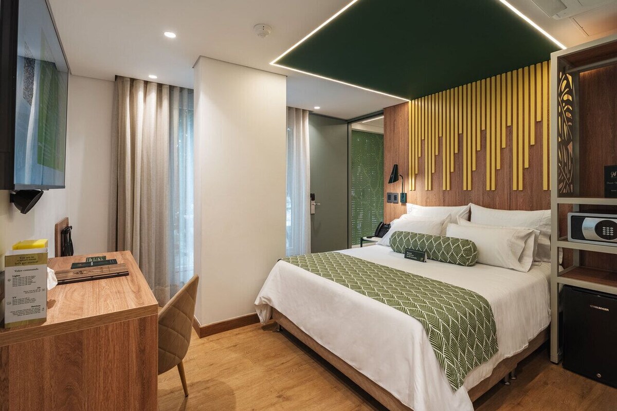 Une chambre d’hôtel équipée d’un lit, d’un bureau, d’une chaise et d’un petit réfrigérateur.