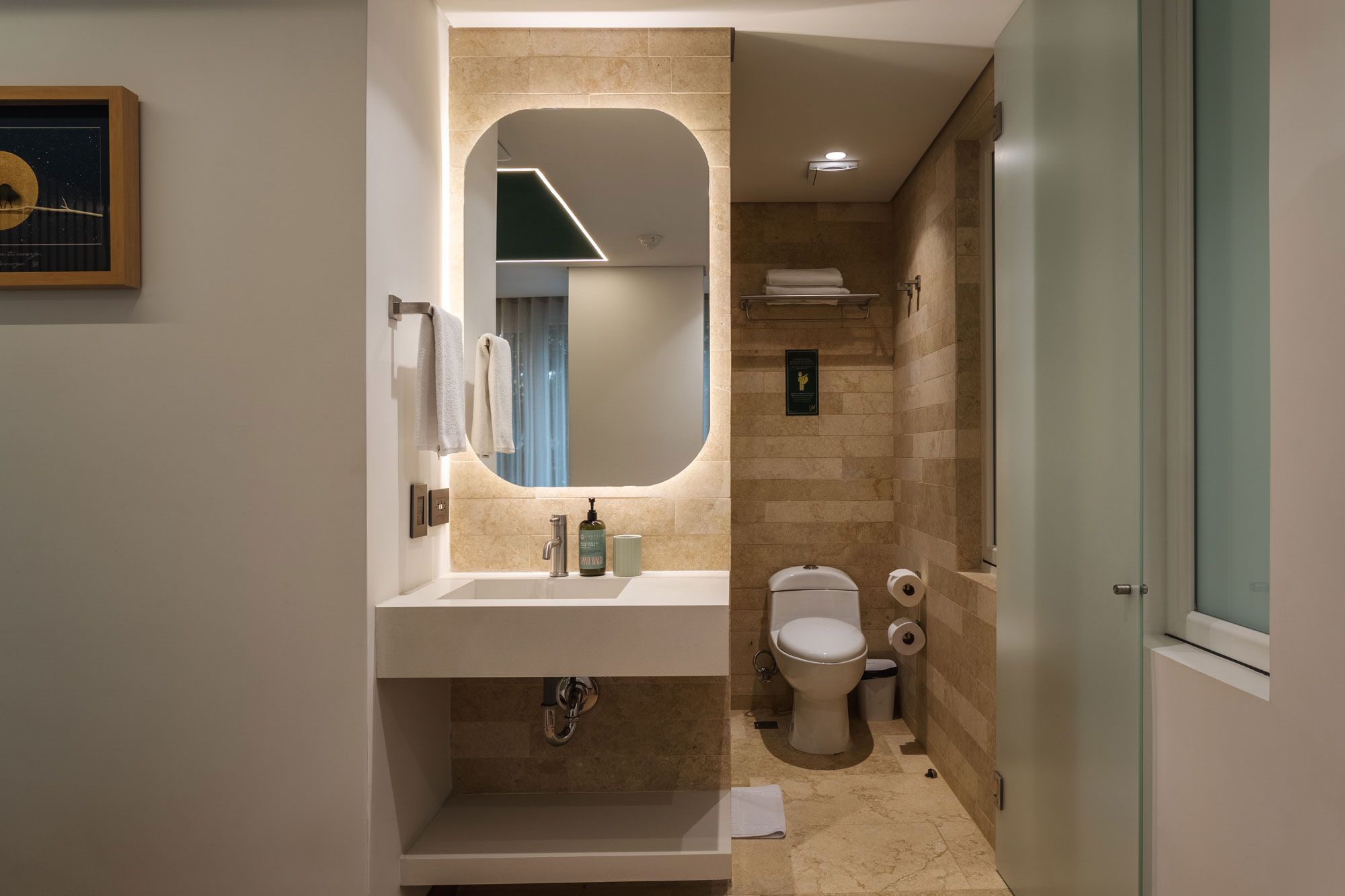 A modern bathroom with a large mirror, a sink, and a toilet.