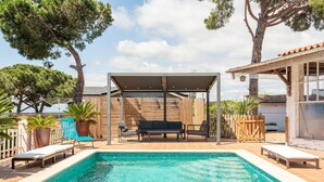 Una piscina amb gandules i una zona de seients coberta.