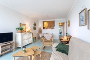 Ein Wohnzimmer mit Fernseher, Sofa und Essbereich mit Tisch und Stühlen.