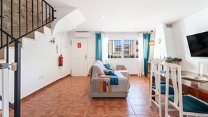 A spacious living area with a sofa, dining table, chairs, a staircase, and a TV. - Holiday Home 'Cozy Townhouse In Soneja' with Mountain View, Wi-Fi and Air Conditioning (Soneja)