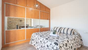 A bedroom with a large bed, wooden wardrobe, and a stone wall.