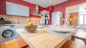 A modern kitchen with a central island, a washing machine, and a dining area with a table set for four. - L'Art Déco - TROYES - City break (TROYES)