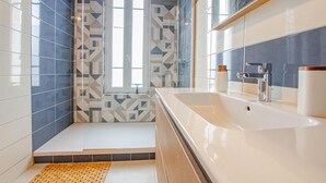 A modern bathroom with a large white sink, a mirror, and patterned tiles. - L'Art Déco - TROYES - City break (TROYES)