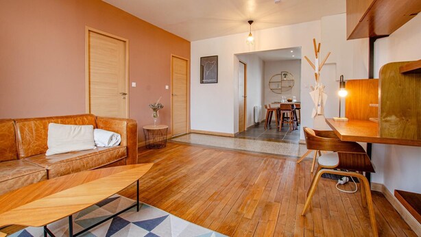 A modern living room with a leather sofa, a wooden coffee table, and a dining area with a wooden table and chairs. - L'Art Déco - TROYES - City break (TROYES)