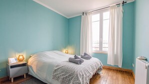 A bedroom with a bed, bedside lamps, a window with curtains, and a radiator. - L'Art Déco - TROYES - City break (TROYES)