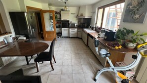 Una cucina con tavolo e sedie, frigorifero, forno, lavandino e una finestra con piante.