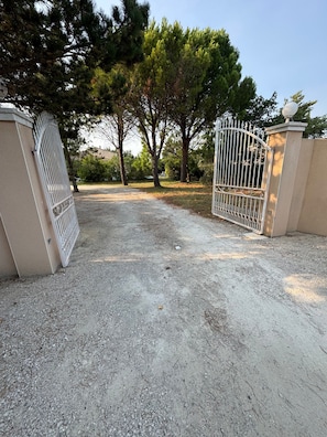 A gated driveway leading to a building with a gravel path.
