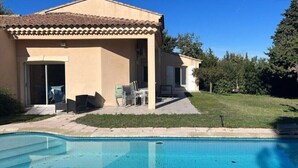 Una casa con piscina, patio con sedie e area esterna coperta.