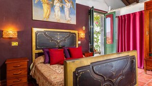 A bedroom with a bed, a dresser, a painting, and a door with curtains.