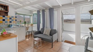 A modern kitchen with a dining area, a sofa with a cushion, and a view of the mountains. - Vacation 'Dangminzheng Atic' with Mountain View and Wi-Fi (Caleta de Caballo)