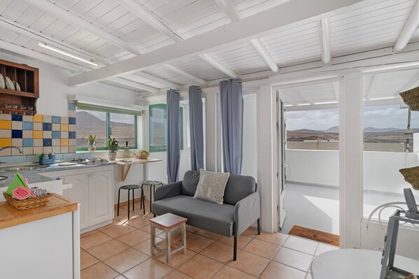 A modern kitchen with a dining area, a sofa with a cushion, and a view of the mountains.