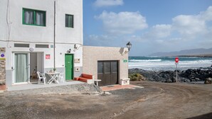 A building with a green door, a table with chairs, and a view of the ocean. - Vacation 'Dangminzheng Atic' with Mountain View and Wi-Fi (Caleta de Caballo)