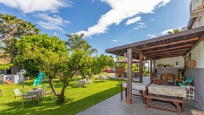 Eine Terrassenfläche mit Außenmöbeln, ein Spielbereich für Kinder und ein überdachter Bereich mit Tischen und Stühlen.