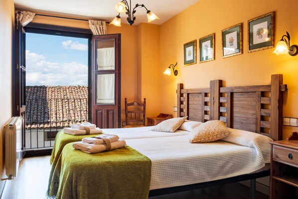 A hotel room with two beds, a balcony, a wooden headboard, and framed pictures on the wall.
