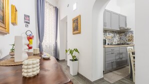 A modern kitchen with grey cabinets, a tiled backsplash, and a wooden dining table with decorative items. - Apartment 'La Dimora Di Elma' with Wi-Fi and Air Conditioning (Palermo)