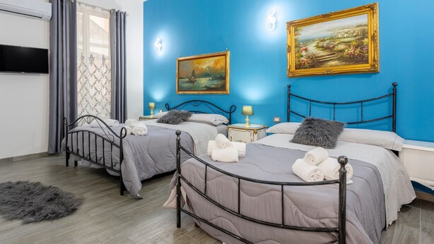 A bedroom with two beds, a TV, and two paintings on the wall. - Apartment 'La Dimora Di Elma' with Wi-Fi and Air Conditioning (Palermo)