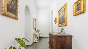 A hallway with a wooden dresser, a vanity with a mirror, and framed artwork on the walls. - Apartment 'La Dimora Di Elma' with Wi-Fi and Air Conditioning (Palermo)