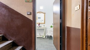 A hallway leading to a bathroom with a mirror, sink, and a small cabinet. - Apartment 'La Dimora Di Elma' with Wi-Fi and Air Conditioning (Palermo)