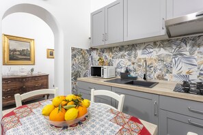 A kitchen with a microwave, sink, and a fruit bowl on the table.