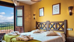 A room with a bed, two bedside tables, a wall-mounted light fixture, and a window with curtains.