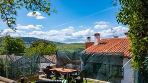 A patio with a table and chairs, a fenced area, and a view of hills.