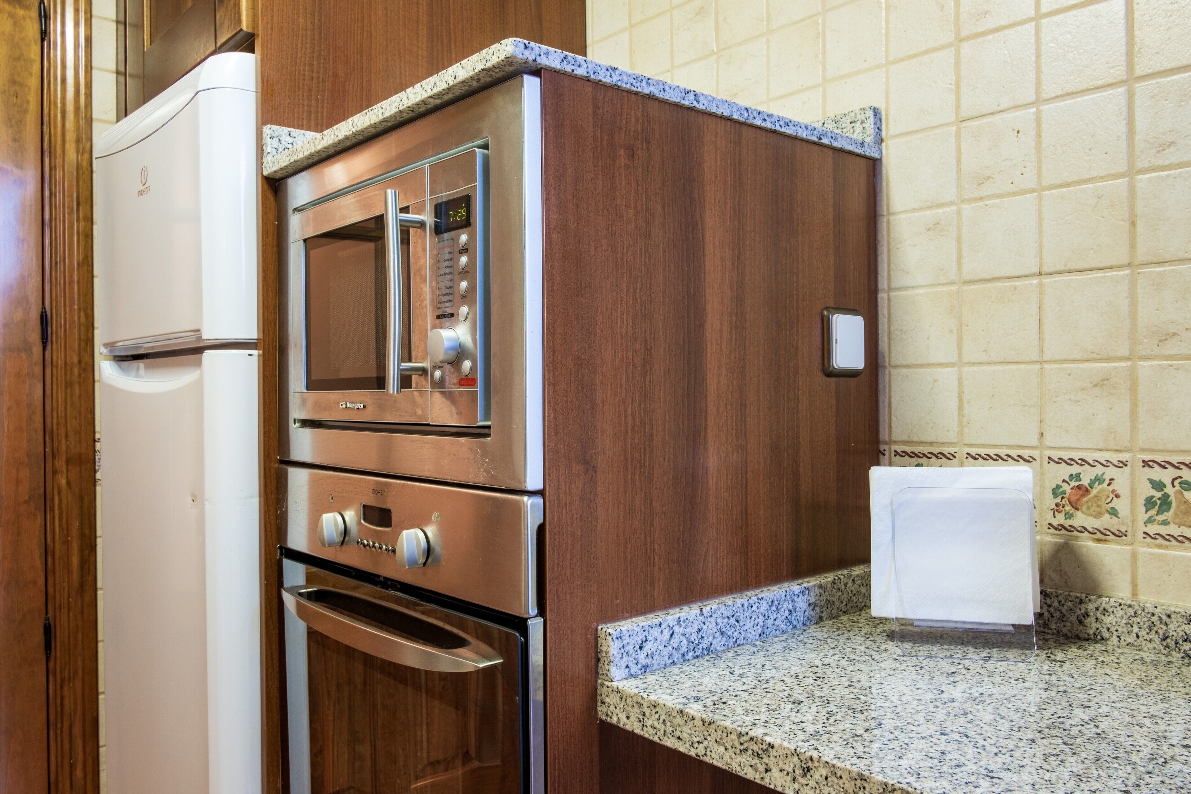 A kitchen with a built-in oven, a microwave, and a refrigerator.