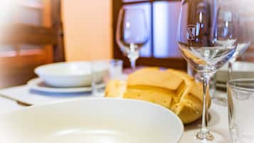 Een eettafel met een wit bord, een glas water en een brood.