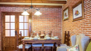 A dining area with a brick wall, wooden table, chairs, and a sofa.