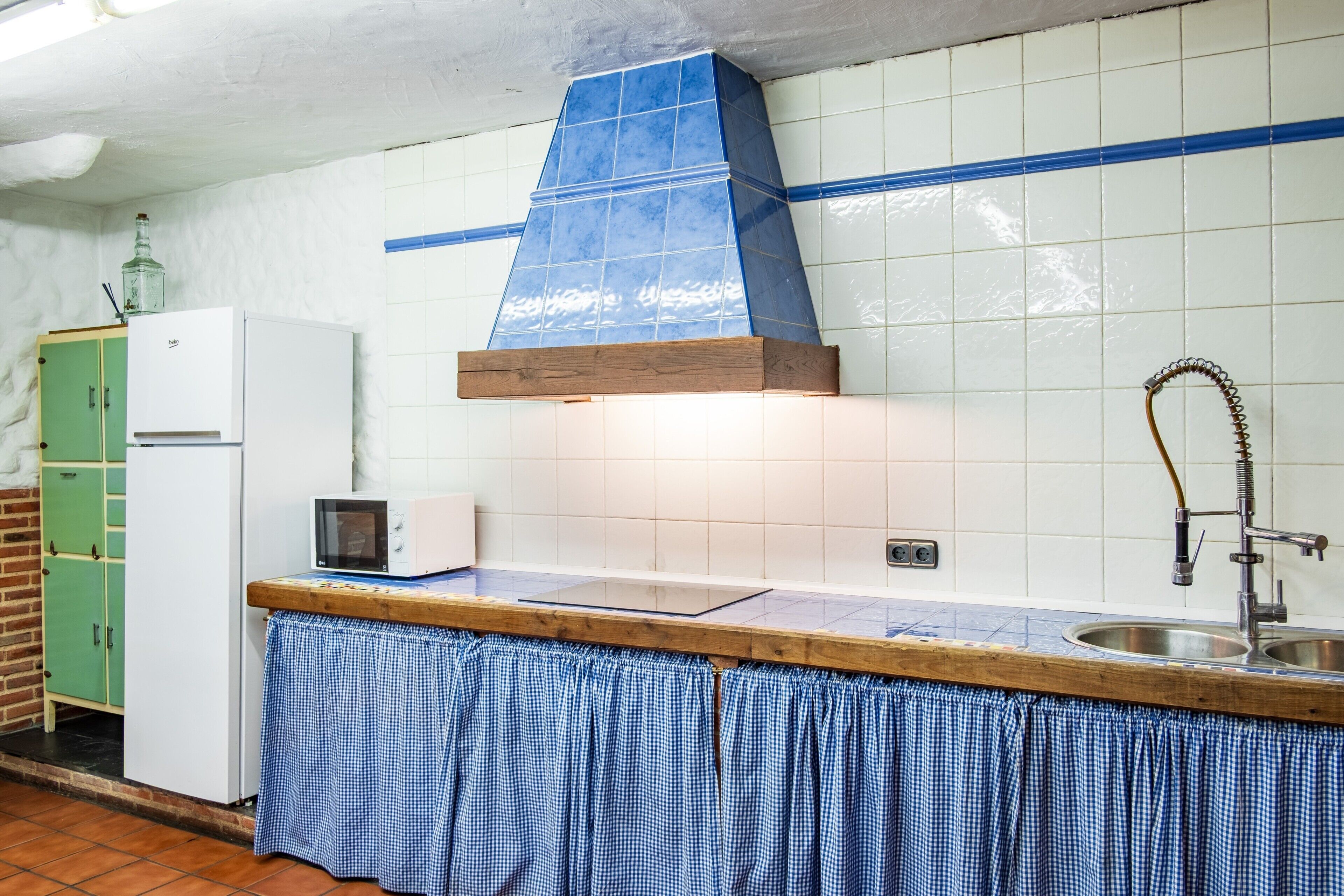 A kitchen with a tiled backsplash, a wooden countertop, a sink, a microwave, and a green cabinet.