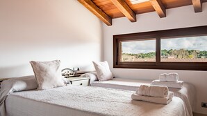 Un dormitorio con dos camas, una ventana con vistas y vigas de madera en el techo.