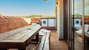 Un patio con una mesa y bancos de madera, una lavadora y un muro de ladrillo.