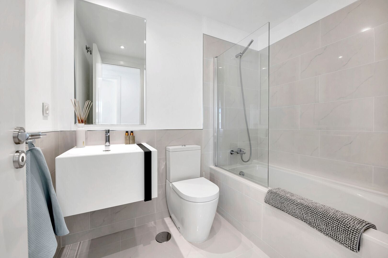 A modern bathroom with a glass-enclosed shower, a white sink, and a toilet.