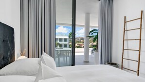 A bedroom with a large bed, a view of the outdoors, a balcony, and a ladder. - Luxury 2-Bed Apartment with Stunning 81 m2 Terrace & Lagoon-Style Pool (Estepona)
