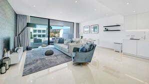 A modern living room with a sofa, coffee table, and a view of the outside. - Luxury 2-Bed Apartment with Stunning 81 m2 Terrace & Lagoon-Style Pool (Estepona)