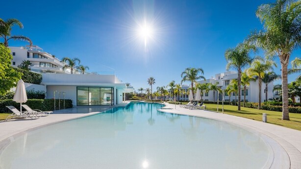 A modern hotel with a large swimming pool, sun loungers, and palm trees. - Luxury 2-Bed Apartment with Stunning 81 m2 Terrace & Lagoon-Style Pool (Estepona)