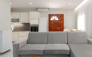 Una cocina moderna con armarios blancos, horno integrado y refrigerador.