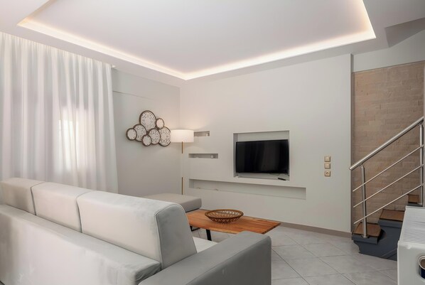 A modern living room with a sofa, TV, and staircase.