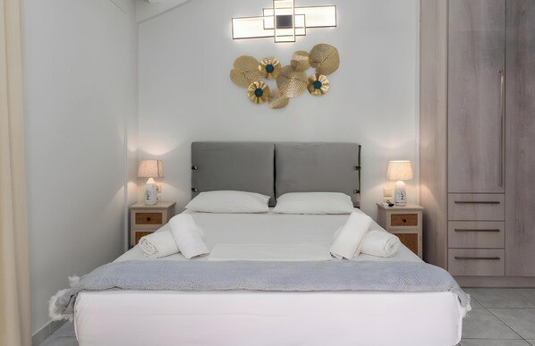 Un dormitorio con una cama, dos mesitas de noche, una lámpara de pared y un armario.