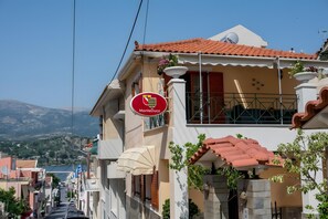 A building with a balcony, a sign reading 'MonteDuca,' and a view of a street and mountains in the background.